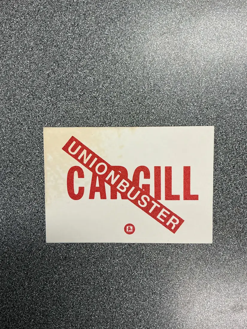 Small rectangular card printed in red ink reading Cargill UNIONBUSTER, with a union label.