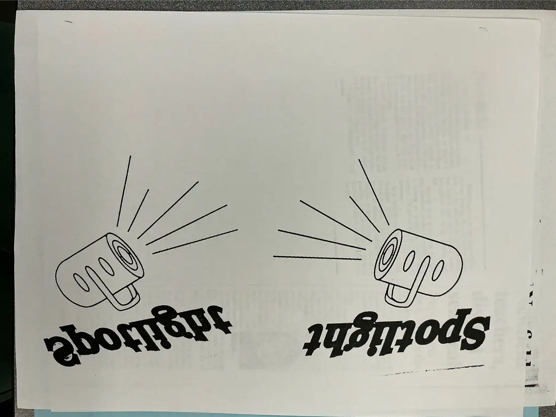 Sheet with two drawings of megaphones above the word Spotlight printed upside down.