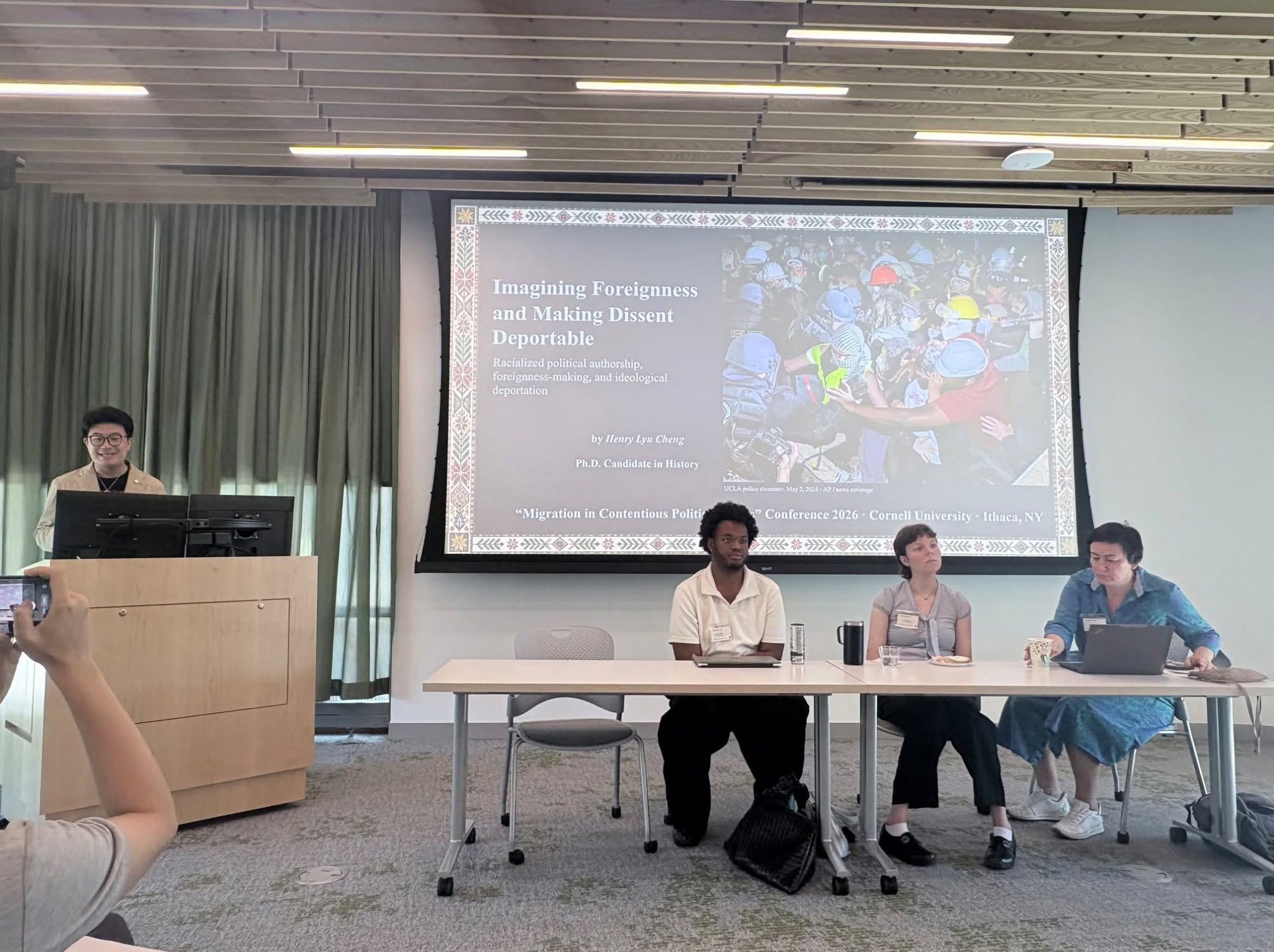 Henry Lyu Cheng presents “Imagining Foreignness and Making Dissent Deportable” as fellow presenters sit at the panel table